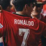 A passionate soccer fan wearing a Ronaldo jersey celebrates at a sports event.