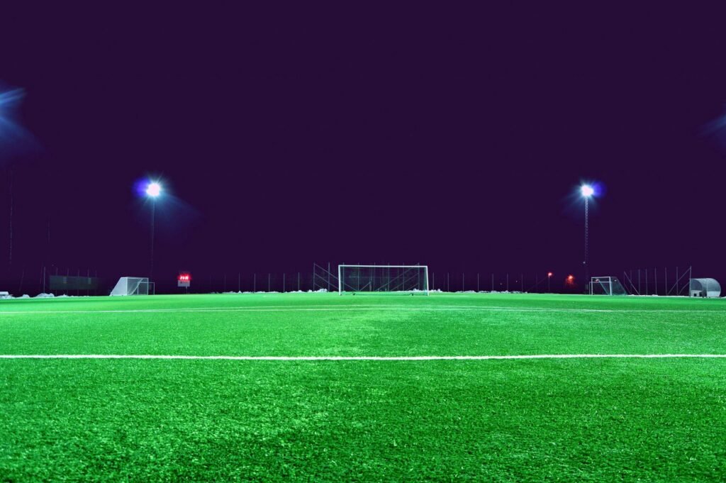 A brightly lit soccer field at night in Norrtälje, Sweden, showcasing green turf and stadium lights.